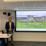 Prof. Martijn Heck standing in front of his presentation title slide