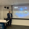 Man standing in front of a lecture screen next to a lectern.