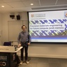 Man standing in front of a lecture screen next to a lectern.