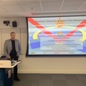 Man standing in front of a lecture screen next to a lectern.